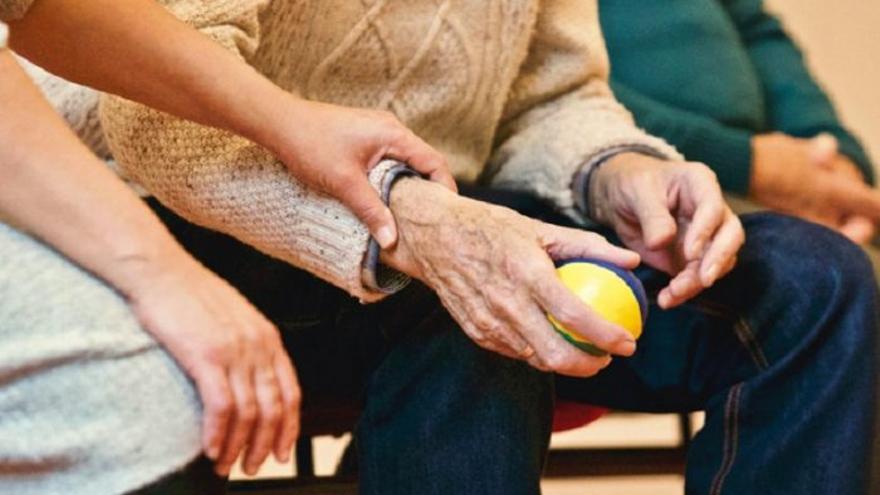 Una mujer coge de la mano a un anciano.