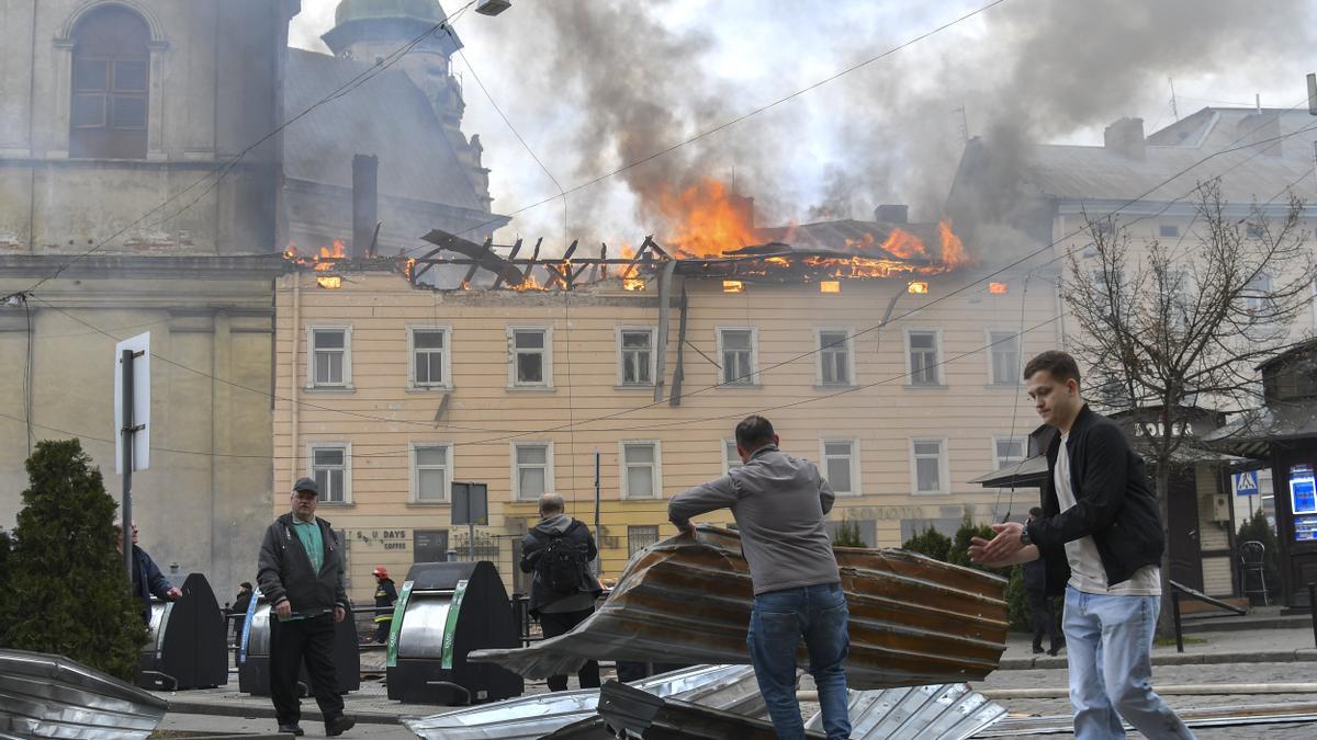 Unas personas retiran los escombros del lugar donde un dron ruso atacó el centro histórico de Leópolis, en el oeste de Ucrania