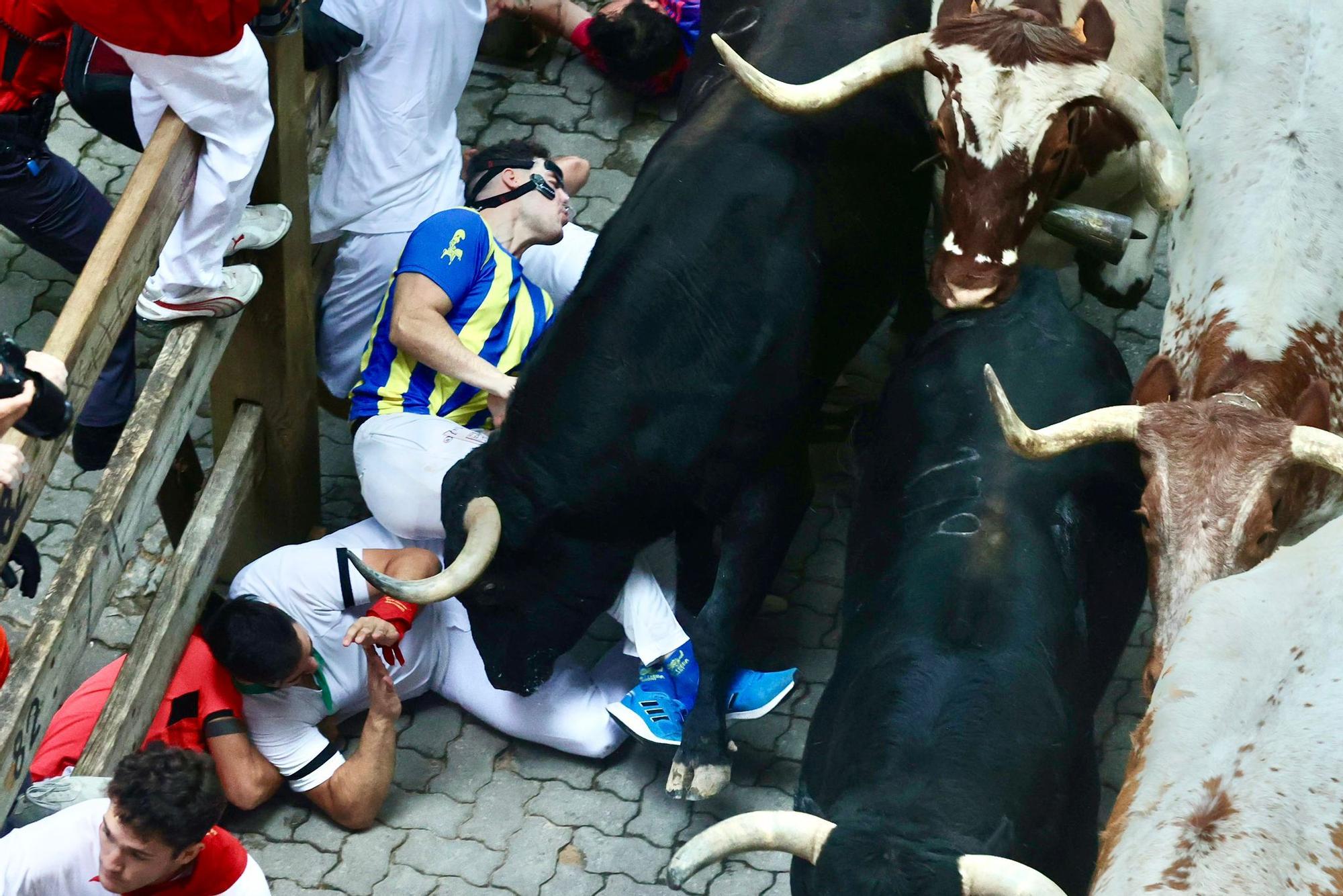 Momento de la bajada al callejón en el que un toro a punto está de empitonar un corredor. Foto: Oskar Montero