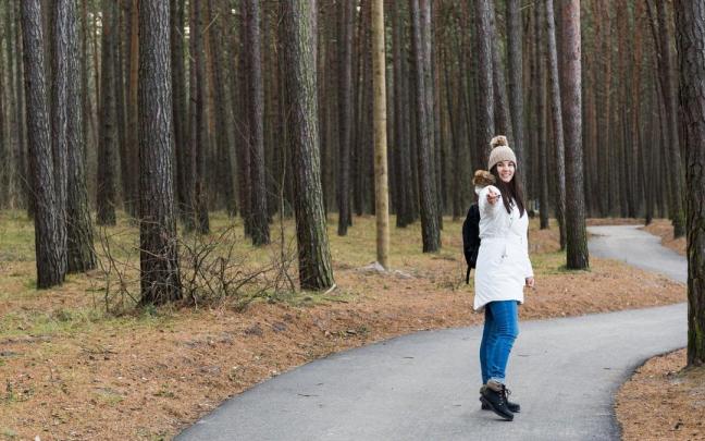 Una mujer se relaja paseando por un camino entre árboles.