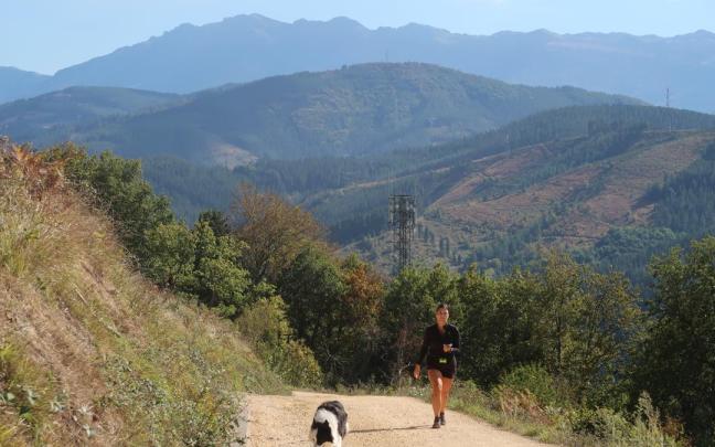 Una zumarragarra pasea por el monte Beloki con su perro.