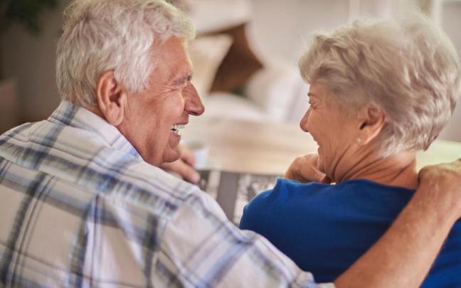 Una pareja de personas mayores sonríen mientras se miran.