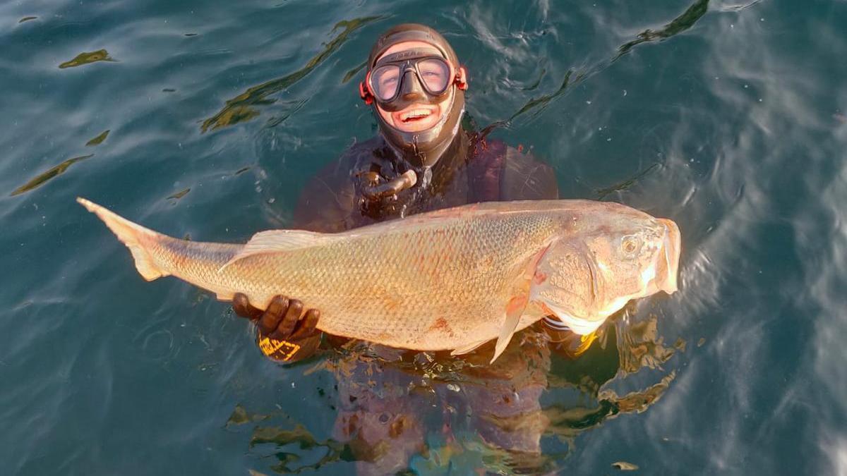 Haritz Ayarza, en el agua, enseñando la lubina que ha capturado.