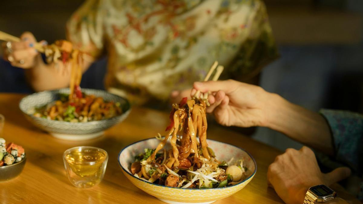 Comer bol de yakisoba con palillos en un rastaurante japonés