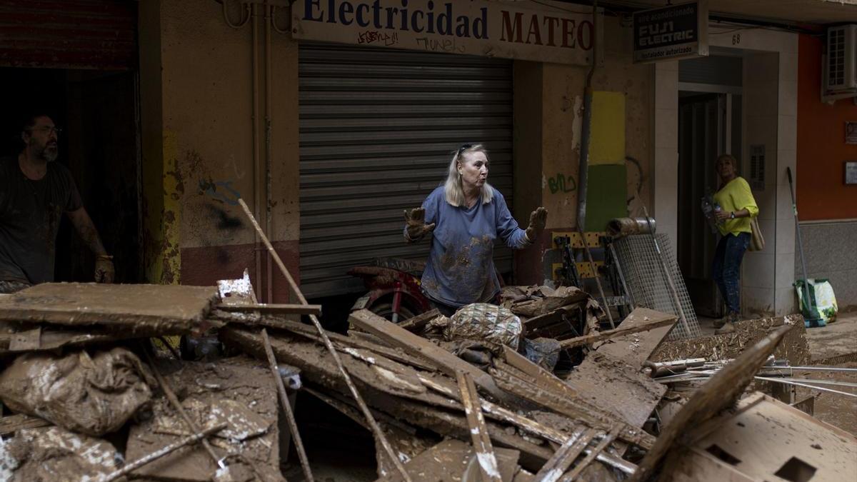 Varias personas retiran agua y barro