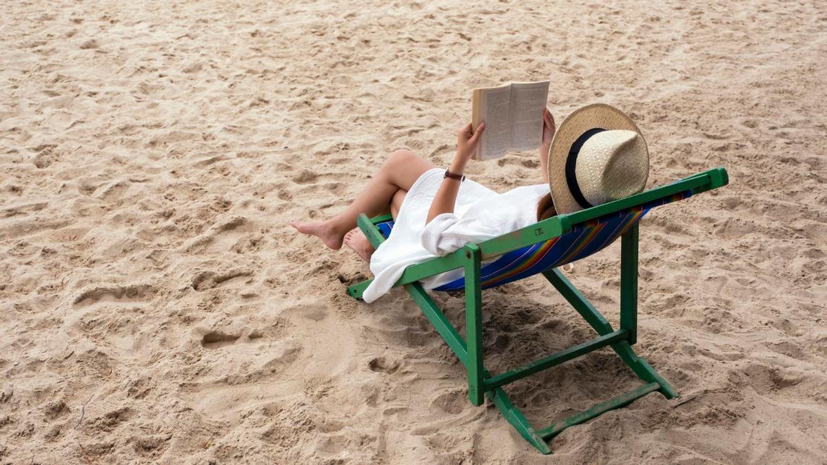 Una mujer lee en la playa.