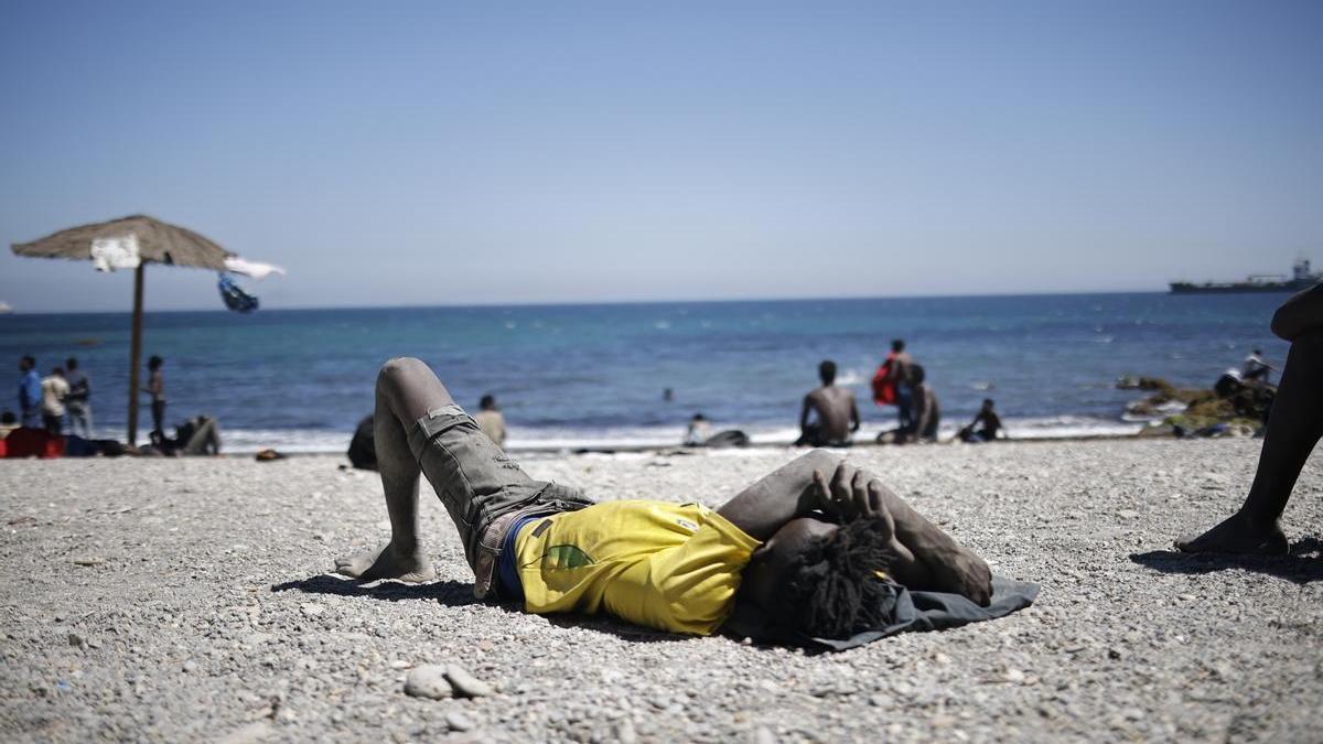 Un joven migrante descansa en una playa de Ceuta.