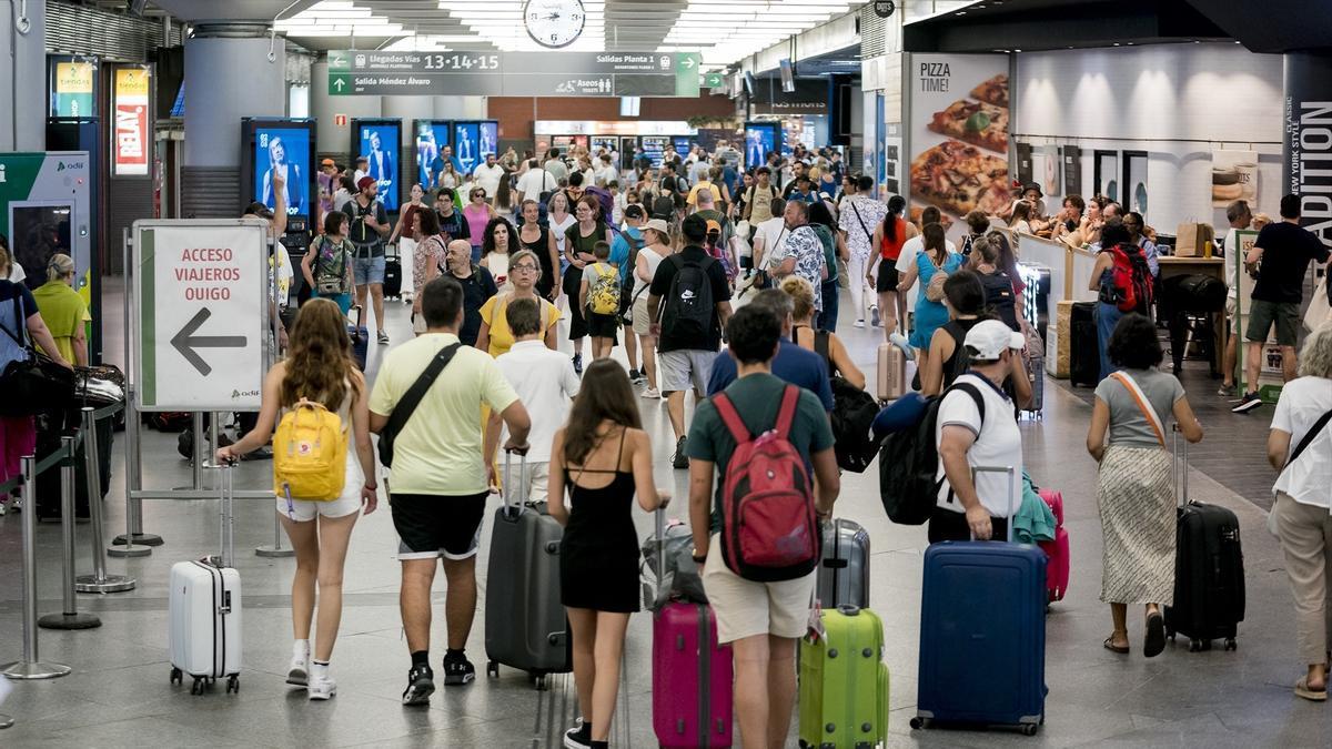 Varias personas con maletas en una estación de Renfe.