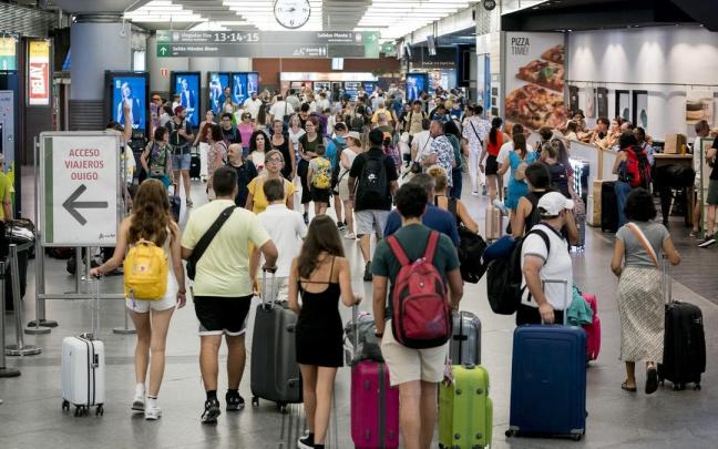 Varias personas con maletas en una estación de Renfe.
