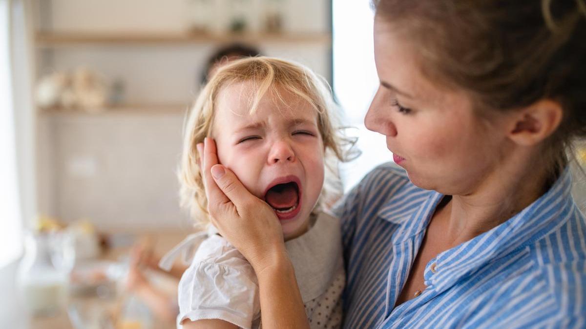 Madre consuela a su hija pequeña en brazos.