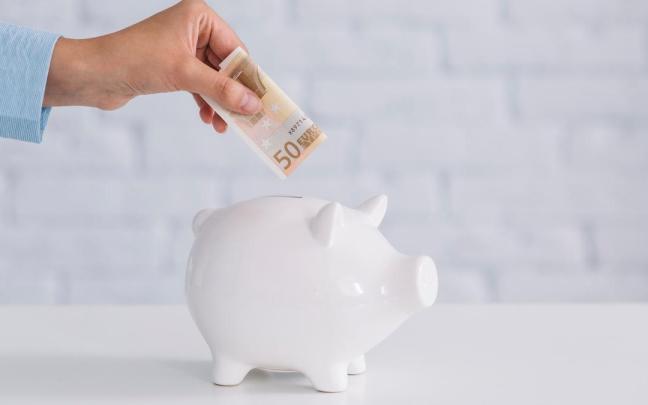 Una mujer introduce un billete de 50 euros en una hucha. Una mujer introduce un billete de 50 euros en una hucha.