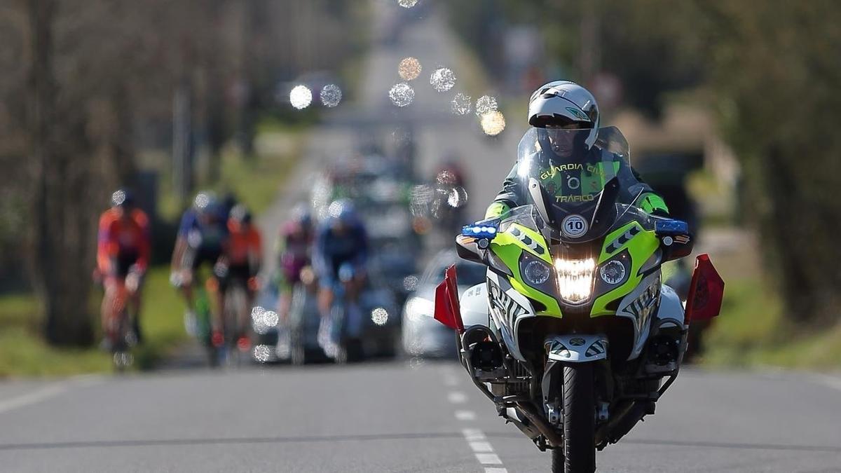Imagen de archivo de un agente de la Guardia Civil de Tráfico junto al pelotón de La Vuelta a España.