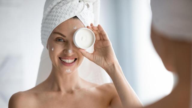 Chica se aplica crema facial al salir de la ducha.