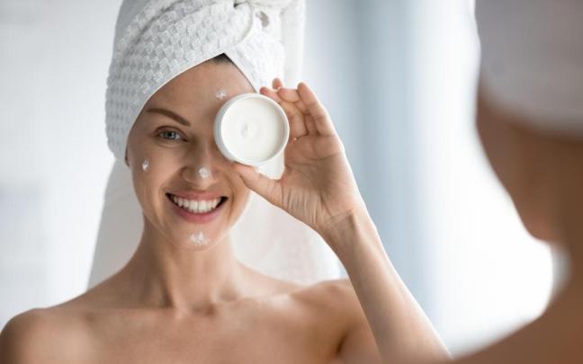 Chica se aplica crema facial al salir de la ducha.