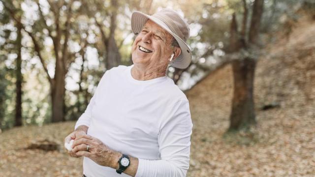 Señor mayor escucha música con unos AirPods mientras da un paseo.