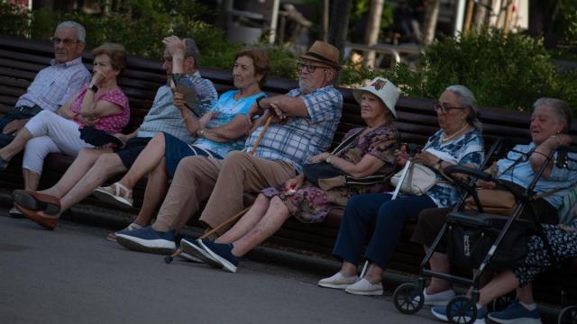 Varias personas sentadas a la sombra protegiéndose del calor.