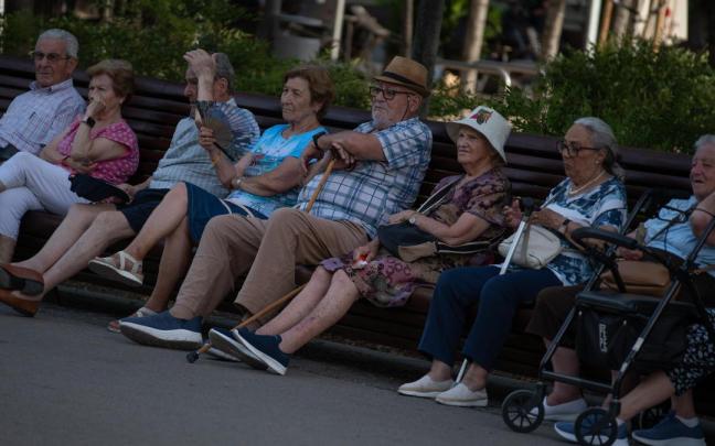 Varias personas sentadas a la sombra protegiéndose del calor.