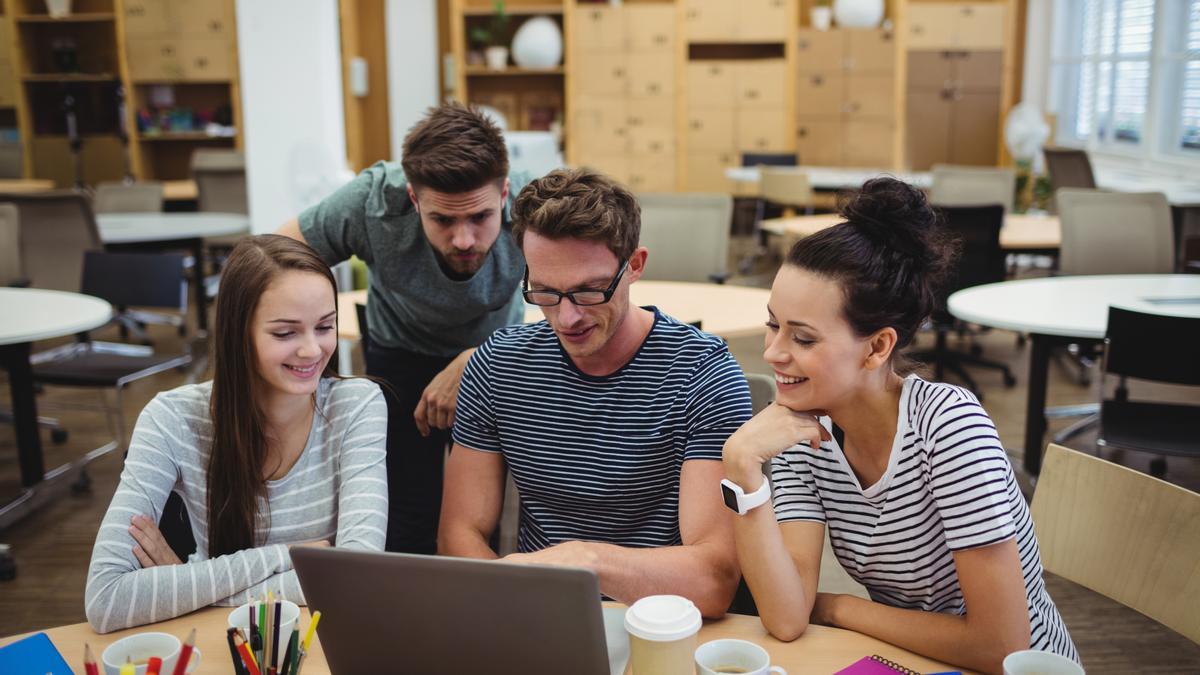 Un grupo de jóvenes miran la pantalla del portátil durante una reunión de trabajo.