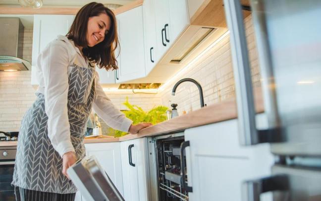 Una mujer sujeta la puerta del lavavajillas.
