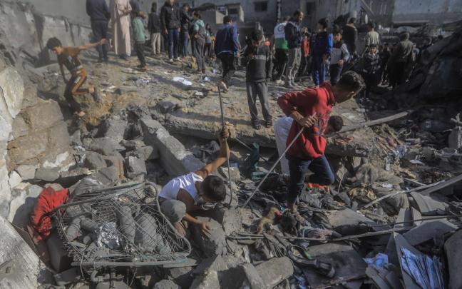 Un grupo de personas buscan entre los escombros de un edificio destruido en Gaza.