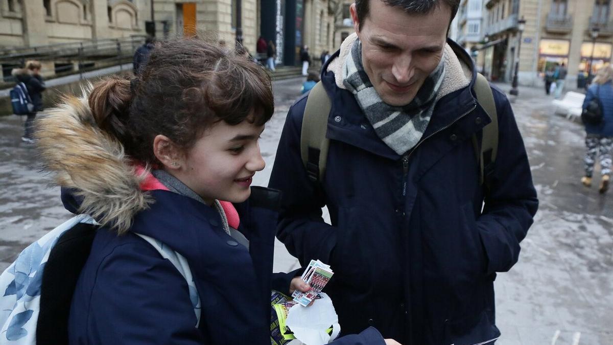 June enseña unos cromos a su aita, Iñigo.