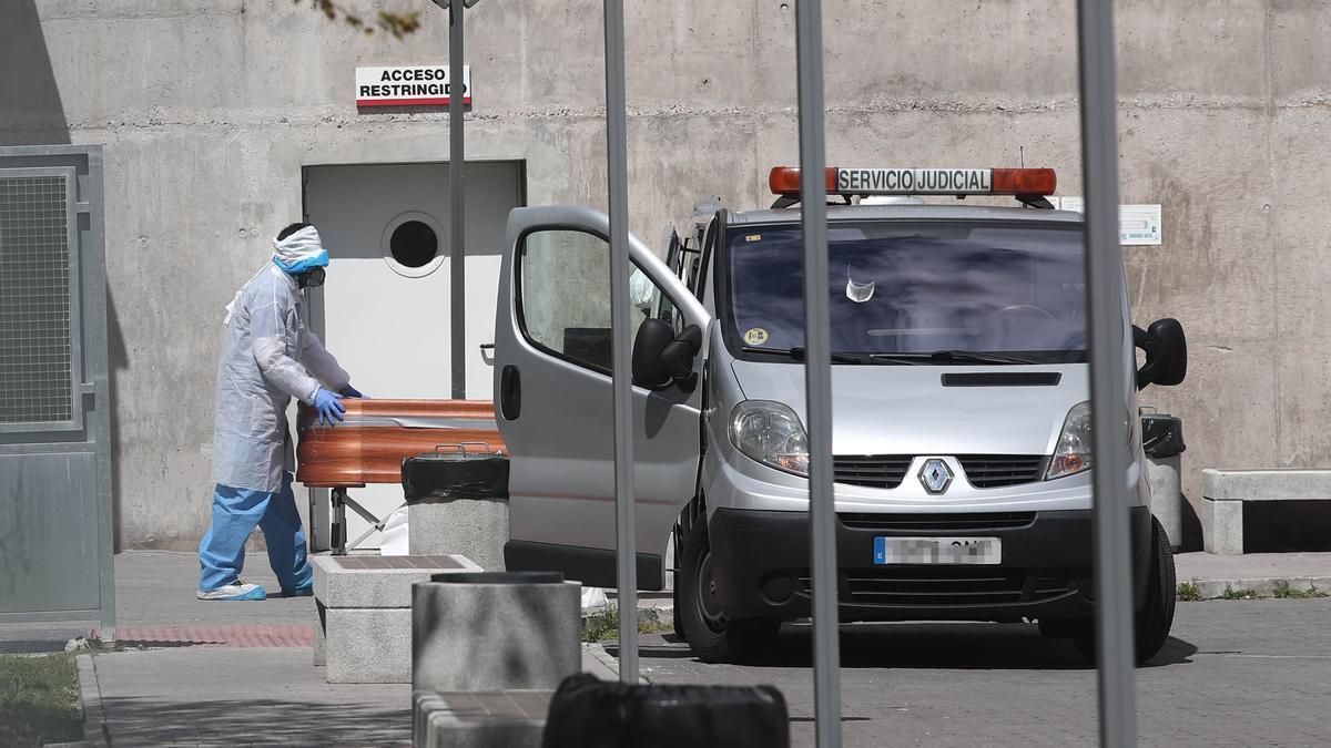 Traslado de un féretro desde una residencia madrileña a un vehículo de intervención judicial.