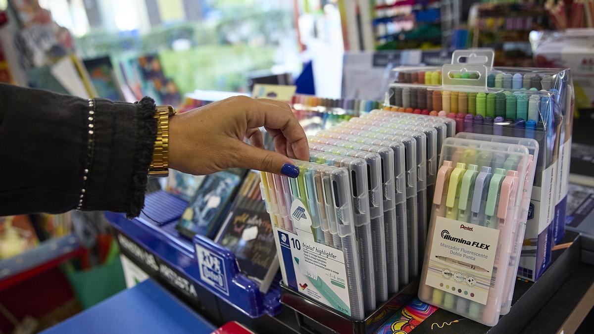 Una mujer coge bolígrafos en una tienda.