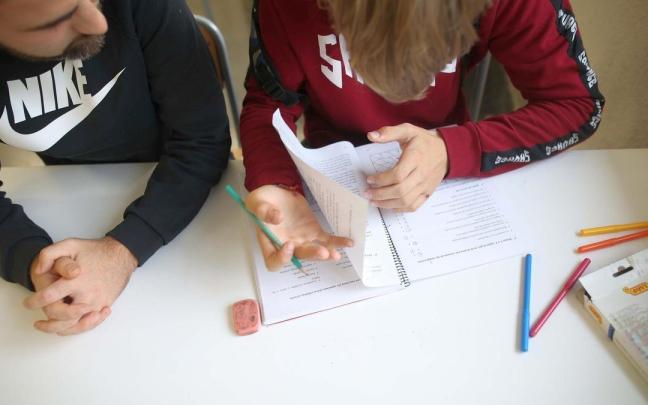 Un profesor ayuda a un estudiante con las tareas escolares en un colegio de Ortuella. Un profesor ayuda a un estudiante con las tareas escolares en un colegio de Ortuella.