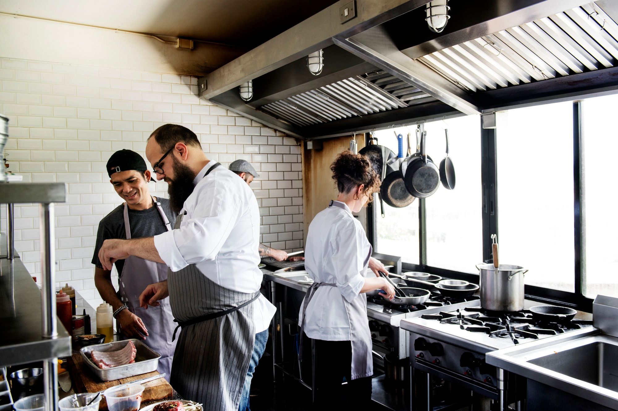 Varias personas trabajan en la cocina de un restaurante.
