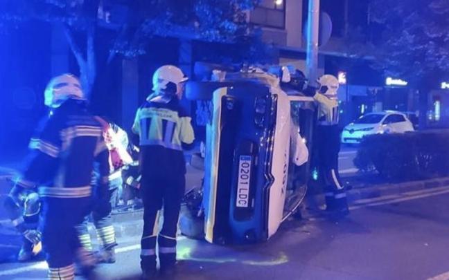 Bomberos juntos al coche patrulla volcado. Bomberos juntos al coche patrulla volcado.