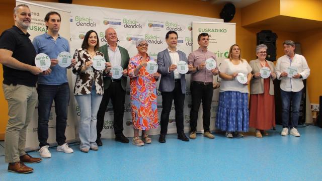 Alcaldes y concejales de la comarca, con el presidente de Bizkaidendak y la directora de Comercio, mostrando las pegatinas de Berriro