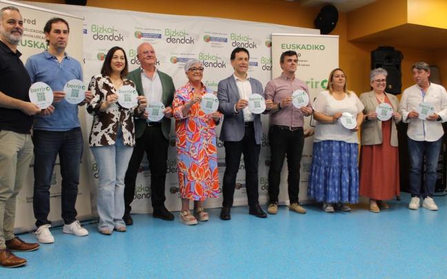 Alcaldes y concejales de la comarca, con el presidente de Bizkaidendak y la directora de Comercio, mostrando las pegatinas de Berriro