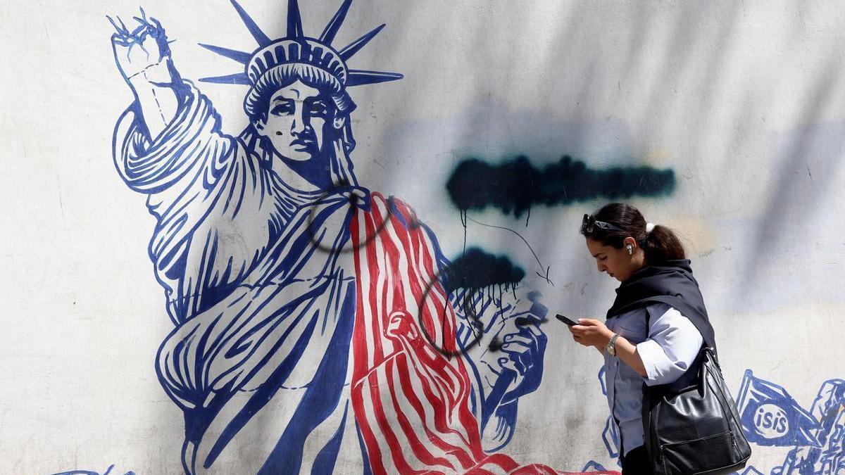 Una mujere iraní camina junto a un mural antiestadounidense cerca de la antigua Embajada de Estados Unidos en Teherán.