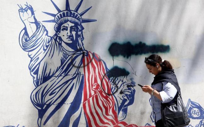 Una mujere iraní camina junto a un mural antiestadounidense cerca de la antigua Embajada de Estados Unidos en Teherán.