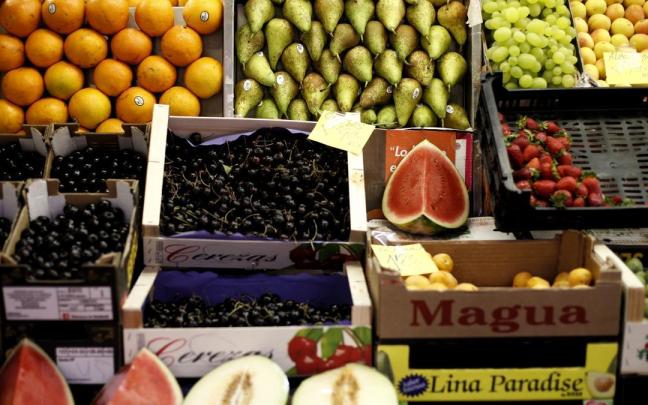 Naranjas, peras, limones, uvas, sandías, melones, fresas y cerezas en un mercado.