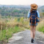 Una mujer camina por un sendero cargando una mochila a su espalda.