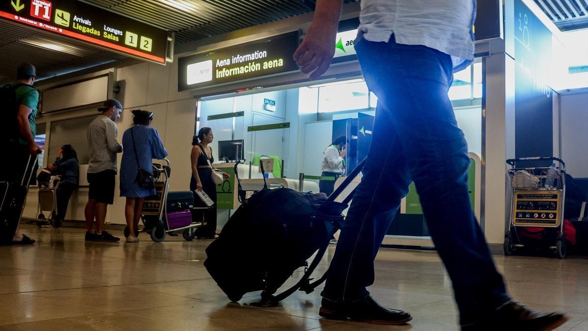 Un hombre transporta su maleta en un aeropuerto