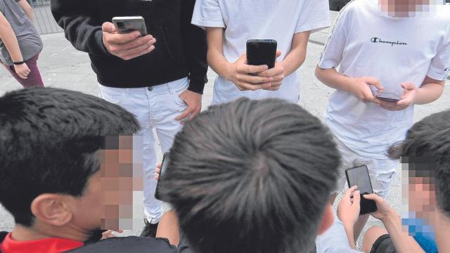 Un grupo de menores, ajenos a esta información, consultan sus teléfonos móviles reunidos en una calle de Bilbao. Un grupo de menores, ajenos a esta información, consultan sus teléfonos móviles reunidos en una calle de Bilbao.