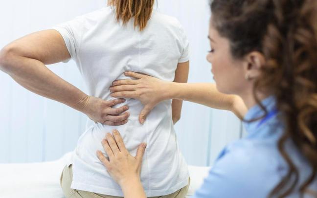 Una médico revisa la espalda de una paciente. Una médico revisa la espalda de una paciente.