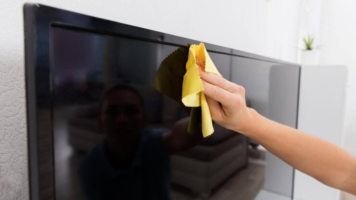 Mano de una mujer limpiando la televisión con un paño muy suave para evitar dañarla