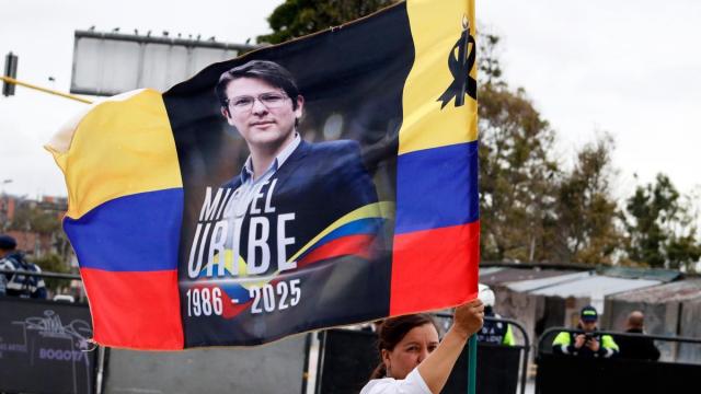 Una mujer ondea una bandera colombiana con el rostro de Uribe.