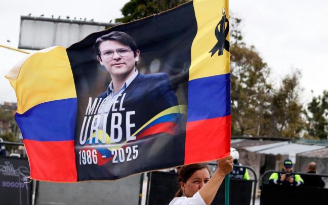 Una mujer ondea una bandera colombiana con el rostro de Uribe.