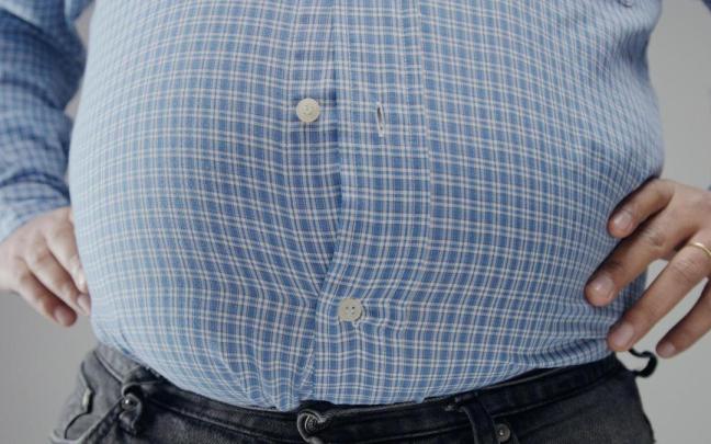 Camisa con un botón desabrochado en una tripa prominente.