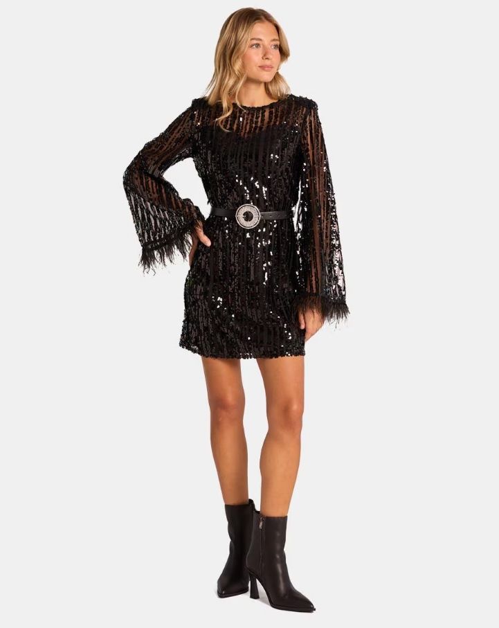 Vestido negro con transparencias y manga acampanada con plumas.