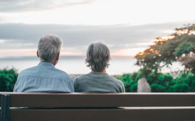 Un hombre y una mujer descansan en un banco mientras disfrutan de las vistas.