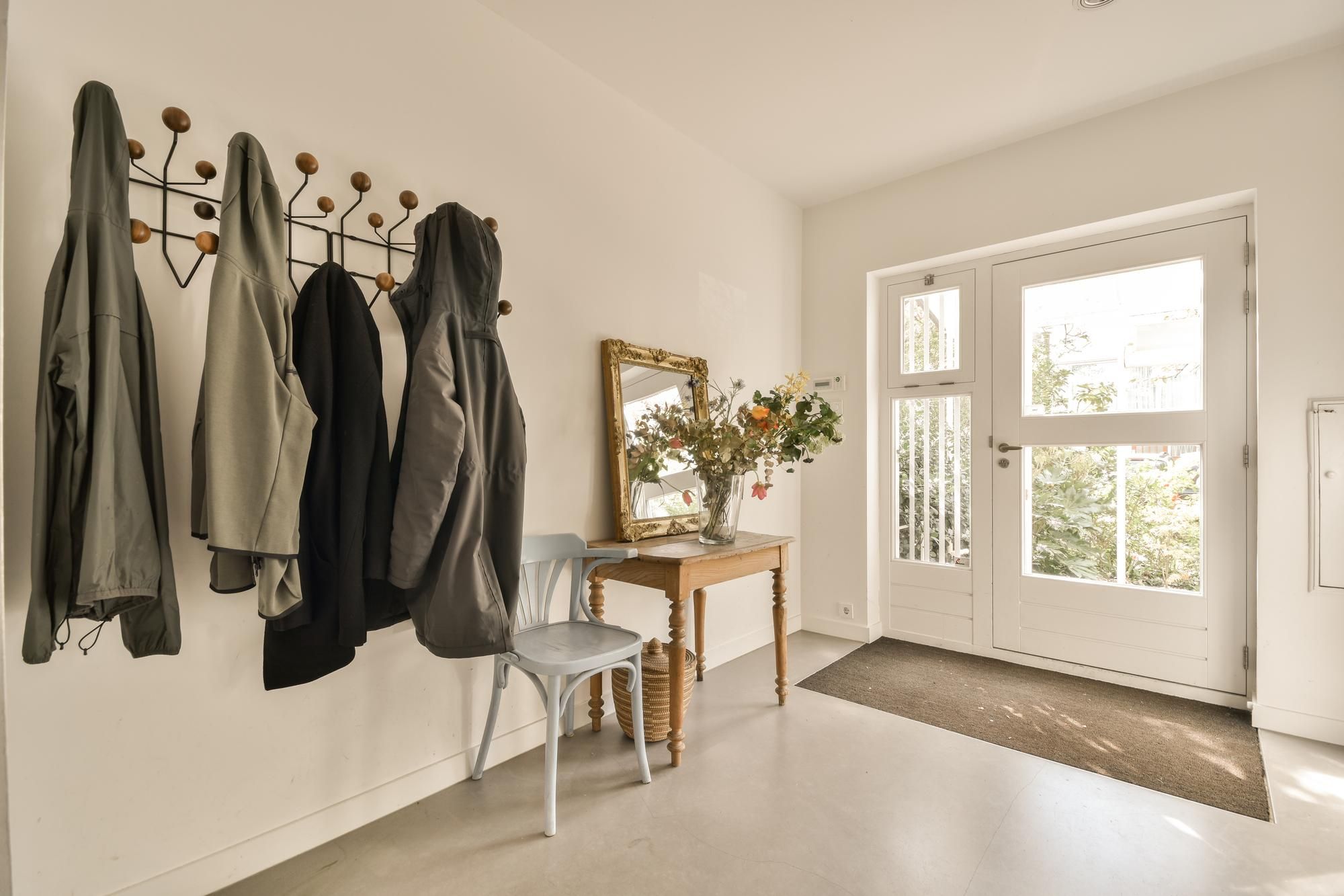 Cuatro abrigos colgados en el perchero de un hall.