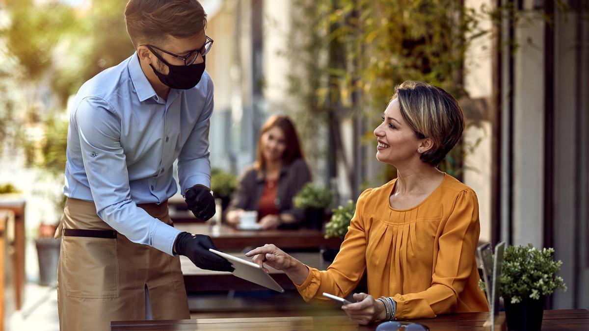 Una mujer pide la cuenta en un local.