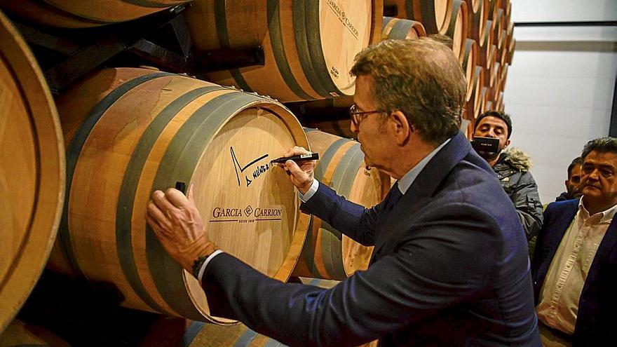 Alberto Núñez Feijóo firma una barrica de vino, ayer durante una visita a una bodega en Daimiel, Ciudad Real. | FOTO: E.P.