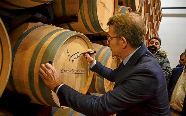 Alberto N&uacute;&ntilde;ez Feij&oacute;o firma una barrica de vino, ayer durante una visita a una bodega en Daimiel, Ciudad Real. | FOTO: E.P.