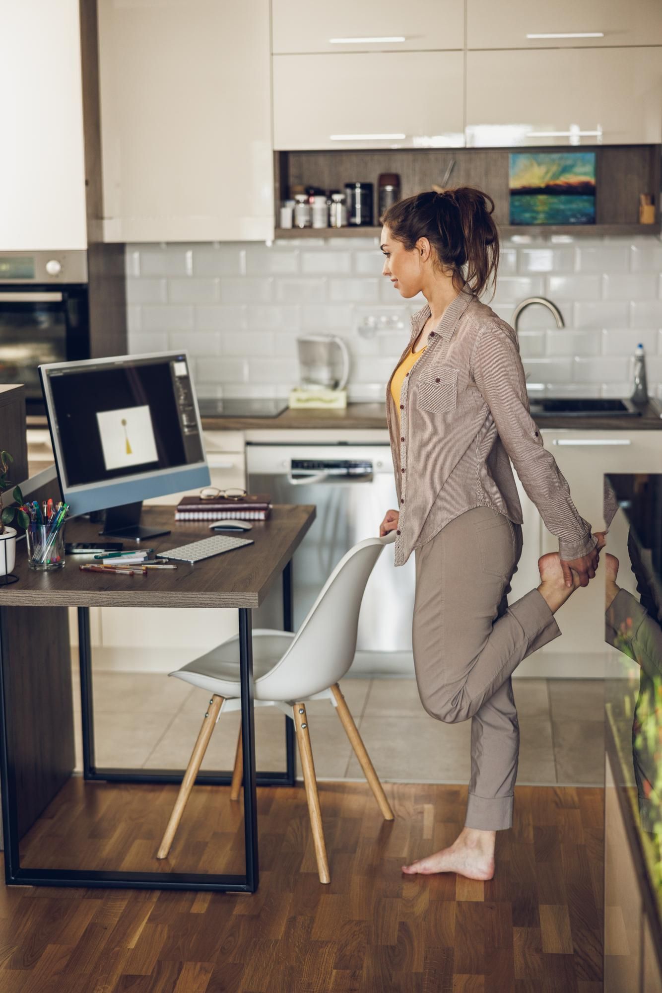 Una mujer hace una pequeña pausa mientras teletrabaja para estirar las piernas.
